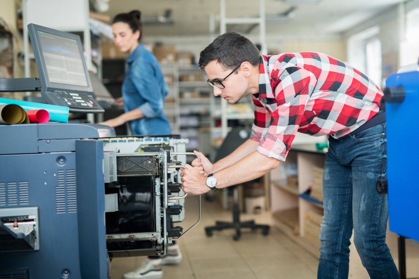 Side view of casual man working with modern printing equipment in contemporary typography office
