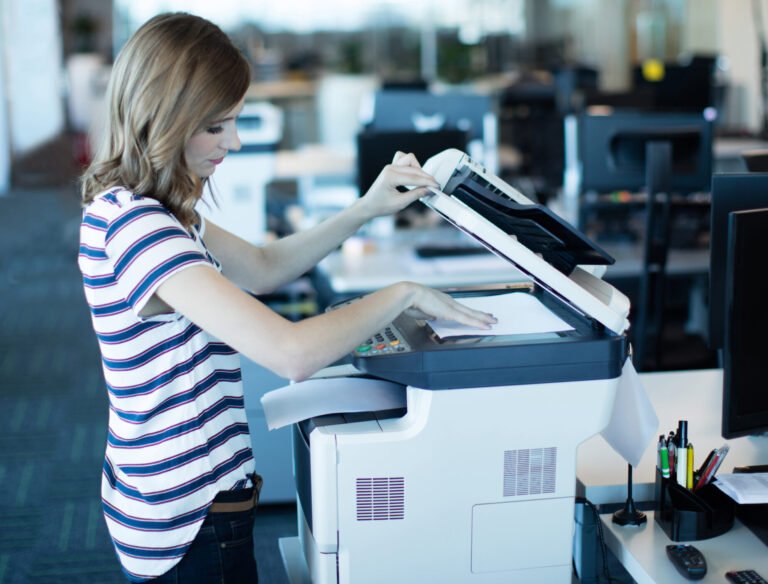 Side view of young businesswoman using copy machine in office